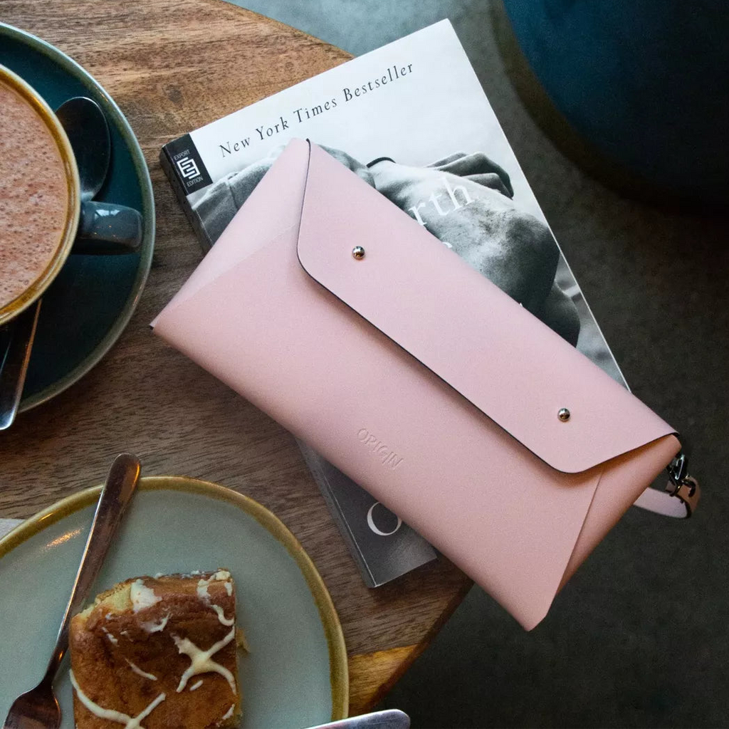 Vaaleanpunainen pikkulaukku kahvilan pöydällä